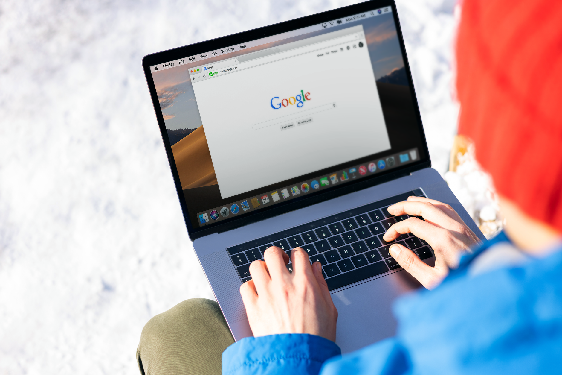 A person typing their name into a search engine on a laptop at a kitchen table.